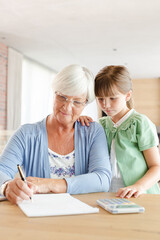 Older woman and granddaughter using calculator