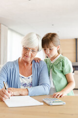 Obraz premium Older woman and granddaughter using calculator
