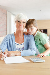 Obraz premium Older woman and granddaughter using calculator