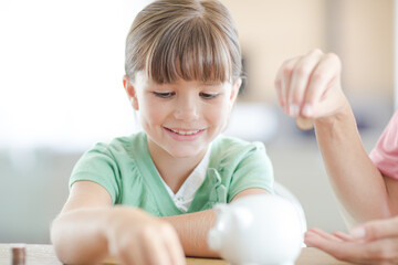 Girl filling piggy bank on counter