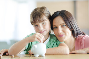 Mother and daughter filling piggy bank