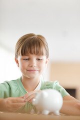 Girl filling piggy bank on counter