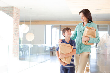 Mother and son posing with shopping bags in kitchen