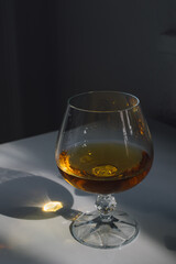 snifter glass of brandy, cognac, whiskey, whisky, bourbon illuminated by sunlight happy hour evening 