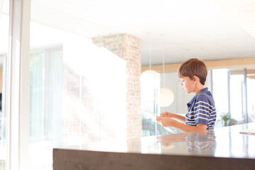 Boy using tablet computer in kitchen