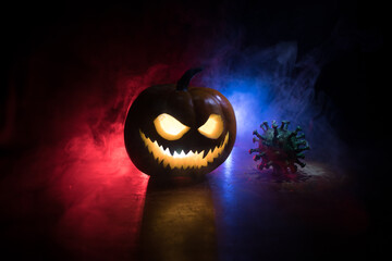 Halloween during Corona virus global pandemic concept. Glowing pumpkins and Covid novel on dark...