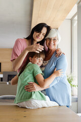 Three generations of women hugging in kitchen