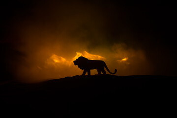 A silhouette of lion miniature standing on wooden table. Creative decoration with colorful backlight with fog. Selective focus
