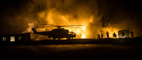 Silhouette of military helicopter ready to fly from conflict zone. Decorated night footage with helicopter starting in desert with foggy toned backlit. Selective focus. War concept © zef art