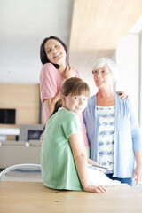 Three generations of women posing in kitchen, smiling