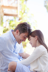 Father and daughter touching foreheads outdoors