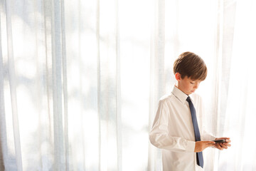 Fototapeta premium Boy in shirt and tie holding smartphone