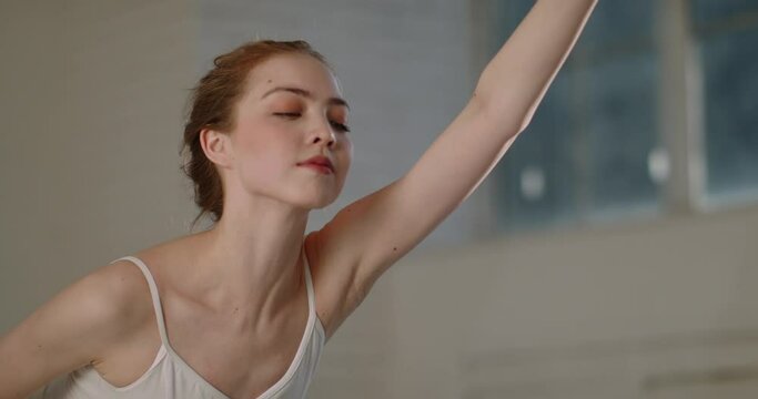 Young beautiful ballet dancer elegantly stretching before starting her practice session. Ballerina reaching out for her toes. 4k footage