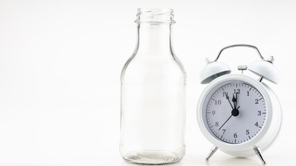 Banner of a glass of milk with white alarm clock on colorful background Copy space