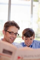 Father and son reading newspaper together