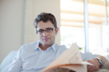 Obraz premium Man reading newspaper on sofa