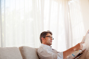 Fototapeta premium Man reading newspaper on sofa