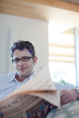 Man reading newspaper on sofa