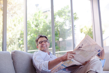 Man reading newspaper on sofa