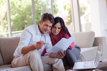 Couple reading papers together on sofa