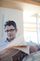 Fototapeta premium Man reading newspaper on sofa
