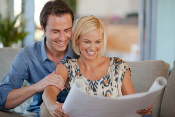 Couple examining blueprints together on sofa