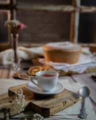 Obraz na płótnie Canvas Xicara de chá em mesa de madeira com bolo ao fundo 