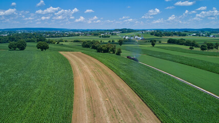 Aerial View of a Steam Locomotive Traveling Across a Fertile Farmland Landscape on a Beautiful Summer Day