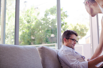 Man reading newspaper on sofa