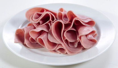 Presunto em fatias formando ondas no prato em fundo branco para recorte.
