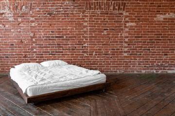 Red brick walls. Large white bed. Modern bedroom