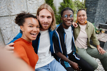 POV diverse group of young people looking at camera via video chat while having fun during outdoor party at rooftop