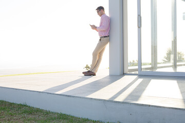 Obraz na płótnie Canvas Businessman using cell phone outside office