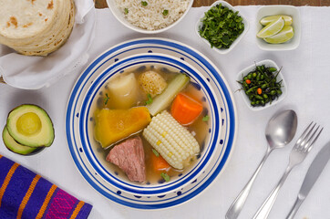 Guatemalan beef soup is made with pieces of meat and vegetables served with rice, vegetables, and tortillas. 