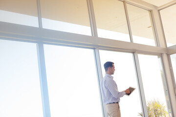 Fototapeta premium Businessman using tablet computer at window