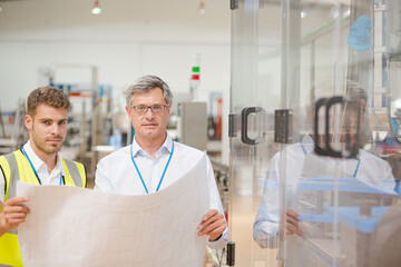 Obraz premium Supervisor and worker reading blueprints in factory