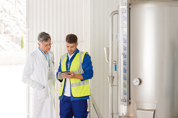 Worker and scientist talking in food processing plant