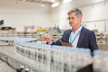 Supervisor examining bottles in factory