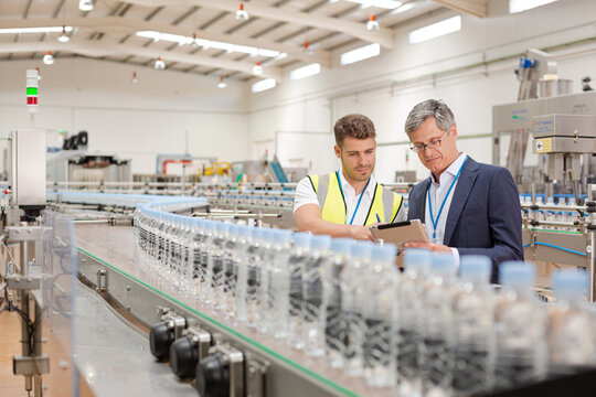 Supervisor and worker using digital tablet in factory - Powered by Adobe