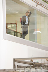 Supervisor leaning on glass window in warehouse