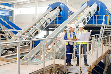 Workers looking at blueprints in recycling center