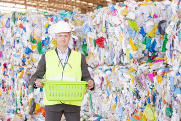 Worker standing by compacted recycling bundles