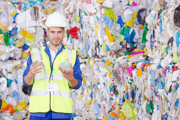 Worker holding compacted plastic bottle in recycling center