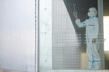 Scientist in clean suit examining liquid in test tube