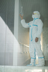 Scientist in clean suit examining liquid in test tube