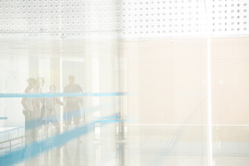 People standng in building behind glass