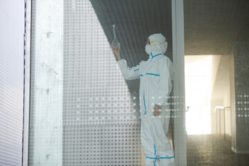 Scientist in clean suit examining liquid in test tube