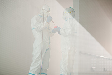 Scientists in clean suit with pipette and tray