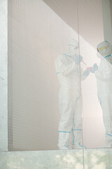 Scientists in clean suit with pipette and tray