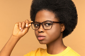 Close up portrait of young pensive African American woman hold glasses looking concentrated at...